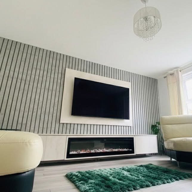 Full room view of slat panel media wall with TV and fireplace