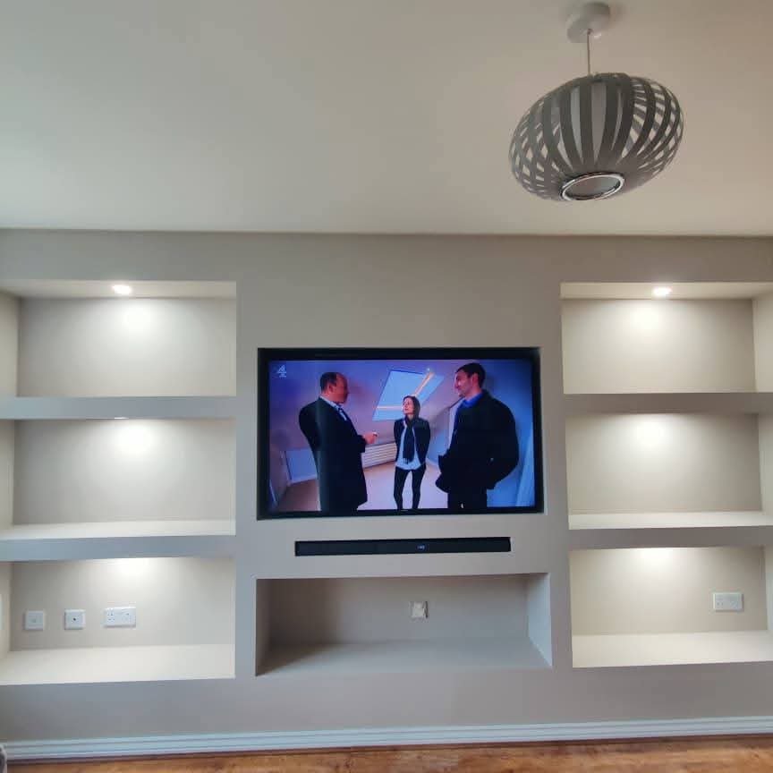 Full width alcove shelving media wall with central TV and LED lighting